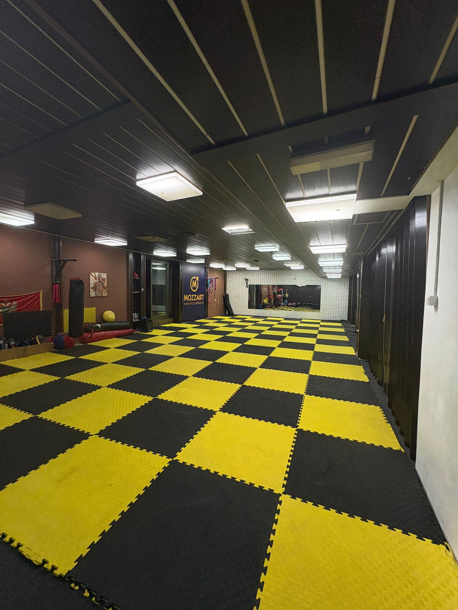 Sala za kik boks — pogled na strunjače, ogledalo i vreću za boks